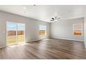 Spacious living room with wood flooring, ample natural light from large windows, and a sliding glass door to the yard at 48255 Shetland Dr, Bennett, CO 80102