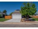 Home exterior showcasing a two-car garage, landscaped front yard, mature tree, and well-maintained lawn at 87 Macon Ct, Aurora, CO 80010