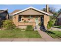 Charming brick home with a cozy front porch, a well-manicured lawn, and tasteful landscaping at 2026 S Lincoln St, Denver, CO 80210