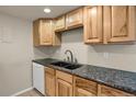 Kitchen featuring wooden cabinets, dark countertops, undermount sink, and white dishwasher at 3675 S Cherokee St # 110, Englewood, CO 80110