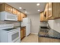 Bright kitchen with white appliances, wooden cabinets, granite countertops, and tile floor at 3675 S Cherokee St # 110, Englewood, CO 80110