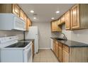 A bright kitchen featuring white appliances, wooden cabinets, dark countertops, and tile flooring at 3675 S Cherokee St # 110, Englewood, CO 80110