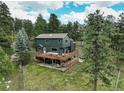 Spacious two-story home featuring a large deck and surrounded by towering trees on a lush green lawn at 31258 Niakwa Rd, Evergreen, CO 80439