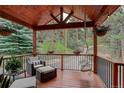 Cozy covered porch with inviting chairs, a hanging swing, and verdant scenery at 31258 Niakwa Rd, Evergreen, CO 80439