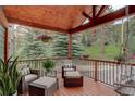 Relaxing covered porch with stylish furniture, hanging flower baskets, and peaceful outdoor views at 31258 Niakwa Rd, Evergreen, CO 80439