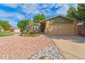 Inviting exterior with a lush front yard, rock features, manicured lawn, and two-car garage at 13849 W 66Th Dr, Arvada, CO 80004