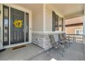 Comfortable porch with seating area, stone accents, and a welcoming front door at 23913 E Swallow Cir, Aurora, CO 80016