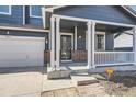 Inviting covered porch with brick accents, white pillars, and a view of the front yard at 10037 Idalia St, Commerce City, CO 80022