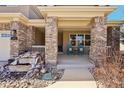 Inviting front porch with brick columns and a peaceful seating area, enhanced by rock landscaping at 8131 S Coolidge Way, Aurora, CO 80016