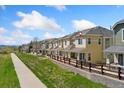 A row of two-story tan townhomes with well-manicured lawns and sidewalks, showcasing a tranquil community setting at 16212 E Geddes Ln # 11, Aurora, CO 80016