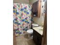 Cozy bathroom with a floral shower curtain, tiled floor, and wooden vanity at 7488 Quivas St, Denver, CO 80221