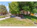 Charming home with a lush green lawn, colorful flowerbeds, and mature trees providing ample shade at 10293 E Sheri Ln, Englewood, CO 80111