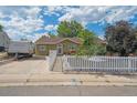 Charming single-story home featuring a welcoming entrance, white picket fence, and well-maintained landscaping at 1817 S Perry Way, Denver, CO 80219