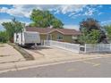 Quaint single-story home with a camper parked nearby, featuring a white picket fence and landscaped front yard at 1817 S Perry Way, Denver, CO 80219