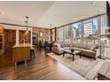 Open-concept living room featuring hardwood floors, exposed brick wall, and large windows with city views at 1401 Delgany St # 409, Denver, CO 80202