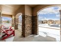 Covered porch with stone columns and red chairs, overlooking a snowy street at 42280 Kingsmill Cir, Elizabeth, CO 80107