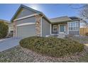 A two-car garage, brick accents, and a blue-green front door creates curb appeal at 5843 S Gray St, Littleton, CO 80123