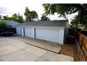 Detached two car garage with white doors and a large driveway at 3111 W Bails Pl, Denver, CO 80219