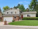 Two-story home featuring a red front door, attached two car garage, and a well-manicured front lawn at 13762 W 67Th Pl, Arvada, CO 80004