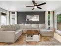 Spacious living room featuring a plush sectional, modern ceiling fan, light wood flooring, and natural light at 23222 E Orchard Pl, Aurora, CO 80015