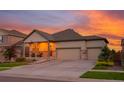 Charming home featuring a welcoming front porch and a three-car garage, set against a colorful sunset at 19468 E 65Th Pl, Aurora, CO 80019