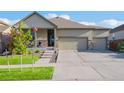 Charming home with a two-car garage, covered porch, stone accents, and attractive landscaping at 19468 E 65Th Pl, Aurora, CO 80019