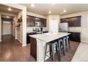 Beautiful kitchen featuring dark cabinets, a large island with seating, and stainless steel appliances at 19468 E 65Th Pl, Aurora, CO 80019