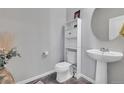 Small bathroom with pedestal sink, toilet, and storage cabinet at 533 Pioneer Ct, Fort Lupton, CO 80621