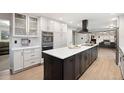 Bright kitchen featuring white cabinets, a black island, stainless steel appliances, and wood floors at 6341 E Floyd Dr, Denver, CO 80222