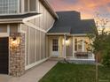 Close-up of the home's entrance with a stone pillar accent, a bench, and a well-manicured lawn at sunset at 11519 Wray Ct, Parker, CO 80134
