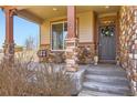 Inviting front porch with stone pillars, seating, and a decorative wreath on the front door at 8768 Foxfire St, Firestone, CO 80504