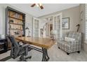 Cozy home office with french doors, a large wood desk, and a comfortable sitting area at 26566 E Peakview Dr, Aurora, CO 80016