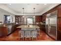 Gourmet kitchen with stainless steel appliances, granite countertops, a central island, and rich wood cabinetry at 4913 Cathay Ct, Denver, CO 80249