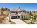 View of stone home with a three car garage and landscaped front yard at 10704 Flowerburst Ct, Highlands Ranch, CO 80126