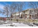 Serene row of townhomes with snow-covered front yards, accentuated by mature trees and a cozy picnic area at 7729 S Cove Cir, Centennial, CO 80122
