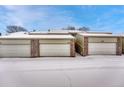 Row of garages featuring brick accents and snow covered roofs at 7729 S Cove Cir, Centennial, CO 80122