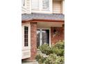 Close-up of the home's front entrance featuring a red brick facade and modern double doors at 12699 W 84Th Dr, Arvada, CO 80005