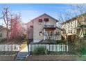 Inviting home with a cozy balcony, red awnings, a well-kept lawn, and a charming white picket fence at 2047 S Franklin St, Denver, CO 80210