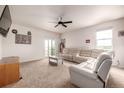 Bright living room with a ceiling fan, white leather sectional and sliding glass door to the backyard at 42425 Forest Oaks Dr, Elizabeth, CO 80107