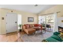 Cozy living room with a brown leather couch, fireplace, sliding glass door to balcony, rug, and bright natural light at 8405 Pebble Creek Way # 202, Highlands Ranch, CO 80126