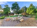 Inviting backyard featuring a fire pit, playground, and manicured lawn with mature trees at 1920 S Niagara St, Denver, CO 80224