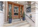 Close-up of the building's elegant wooden front door with stylish potted plants and secure entry system at 1210 E Colfax Ave # 301, Denver, CO 80218