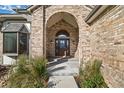 Inviting front entryway featuring a brick archway, decorative glass door, and manicured front garden at 5284 Taft Ct, Arvada, CO 80002