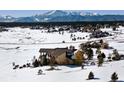 A sprawling home nestled in a snow-covered landscape with majestic mountain views in the distance at 19155 Lochmere Ct, Monument, CO 80132
