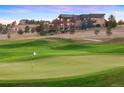 Picturesque view of a lush green golf course with a luxurious home in the background on a rolling hill at 19155 Lochmere Ct, Monument, CO 80132