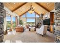 Bright living room with vaulted wood ceilings, a stone fireplace, and large windows that offer a scenic view at 19155 Lochmere Ct, Monument, CO 80132