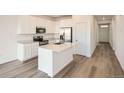 Modern kitchen with white cabinets, island, and stainless steel appliances at 4847 Astor Pl, Brighton, CO 80601