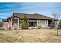 A rear view of the home showcases a cozy covered patio, well-kept yard, and stone and siding finishes at 25019 E Alder Dr, Aurora, CO 80016