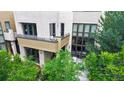 Modern townhouse with large windows, balcony, and cozy patio surrounded by lush greenery at 8041 E 29Th Ave, Denver, CO 80238