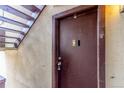 Brown apartment entry door featuring a code pad, lock, and stairs nearby at 9725 E Harvard Ave # 317, Denver, CO 80231